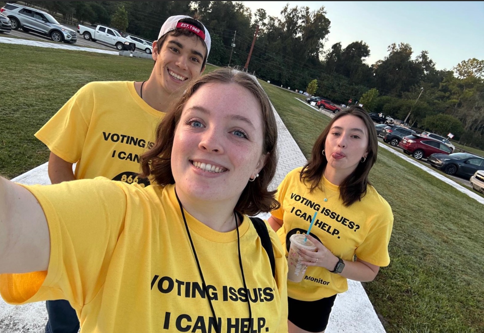 Three young voting monitors wearing yellow voting assistance shirts