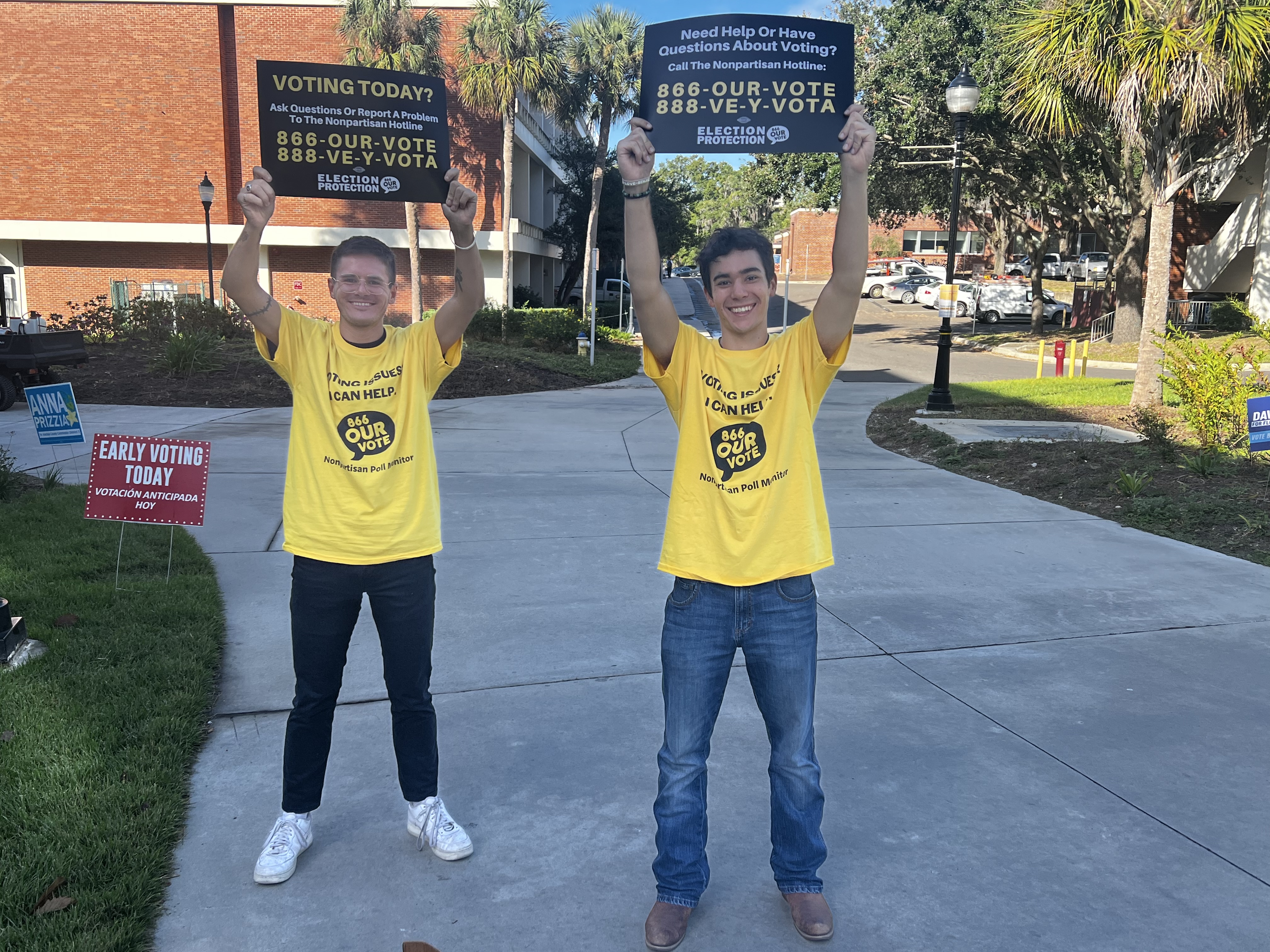 Two young poll monitors holding election protection hotline signs